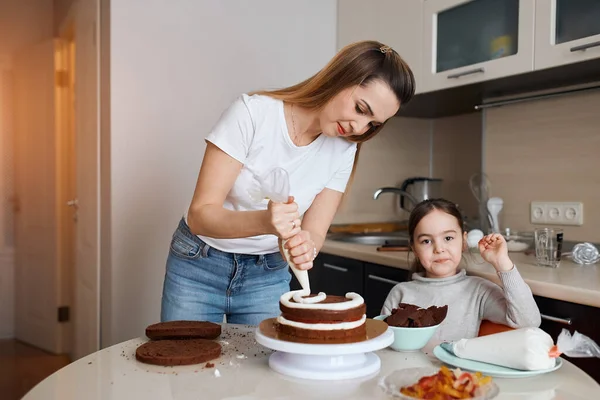 Young woman in T-shirt an djeans concentrated on decorating dessert — Stock Photo, Image