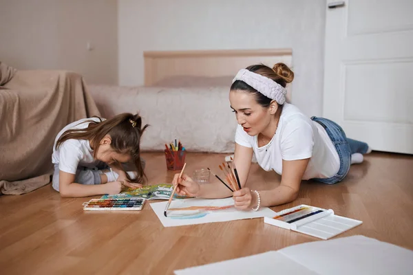 Fiatal nő és lánya élvezi rajz, festés folyamat — Stock Fotó