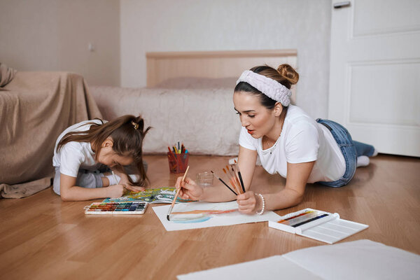 young woman and her daughter enjoying drawing, painting process