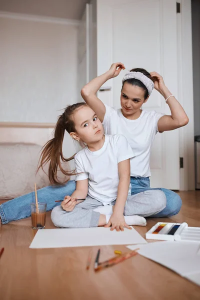 Slim getalenteerd meisje tekening een beeld met haar moeder — Stockfoto