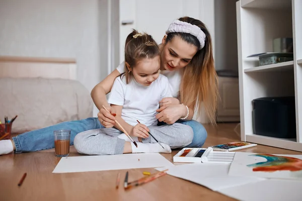 Jonge vrouw en haar dochter geconcentreerd op schilderproces — Stockfoto