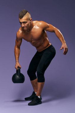 Güçlü, terli, sporcu. Kettlebell ile çalışıyor.