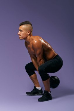 Çömelme hareketleri yapan ciddi çalışkan bir adam, gri bir arka planda izole edilmiş.