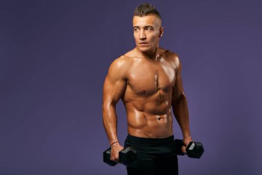 Genç seksi çıplak adam dambıllarla egzersiz yapıyor.