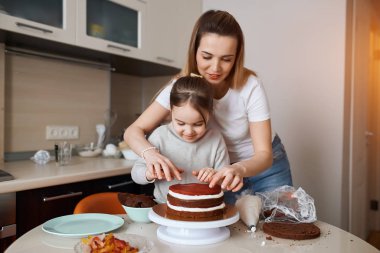 Genç kadın ve çocuğu birbirlerine sünger parçaları sürüyorlar.