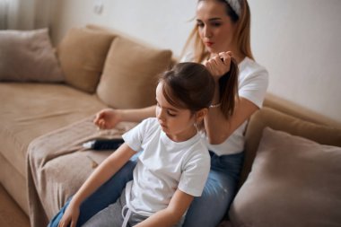 Anne evde küçük bir kız için saç stili yapıyor.