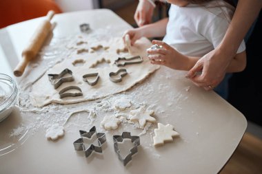 Çocuk mutfakta kurabiye keskisi kullanıyor.