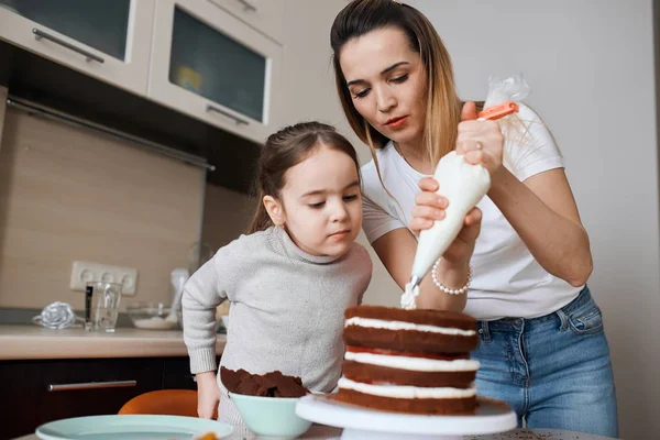Serious little girl and her sisiter preparing cake for their mother — Stock Photo, Image