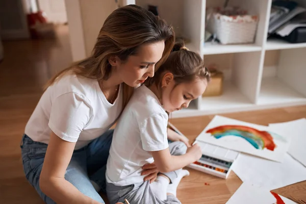 young woman giving advice recommendations while her little kid is painting