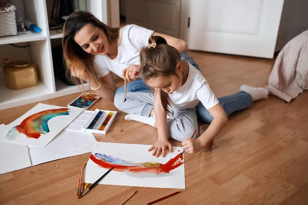 Talentfull jente er glad i å male på gulvet – stockfoto