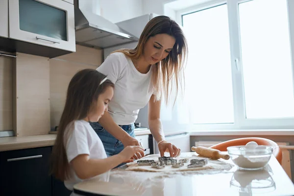 Mladá žena ukazující, jak stříhat tvary cookies — Stock fotografie