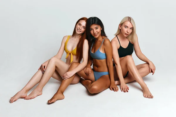 Przyjemna opalona dziewczyna i jej przyjaciele reklamujący nową kolekcję strojów kąpielowych — Zdjęcie stockowe