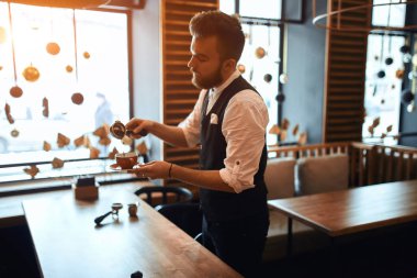 bearded talented barista spilling coffee into the cup