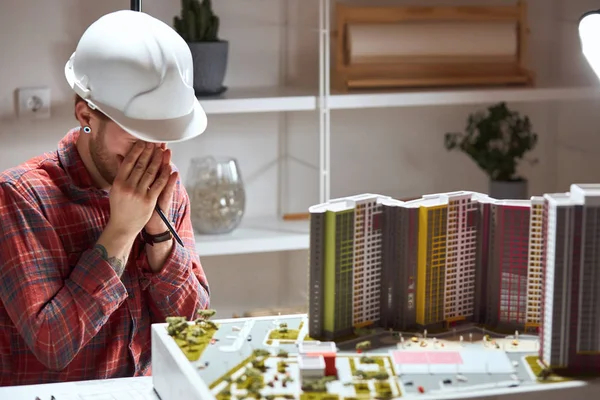 depressed tired architect closing his eyes with arms,