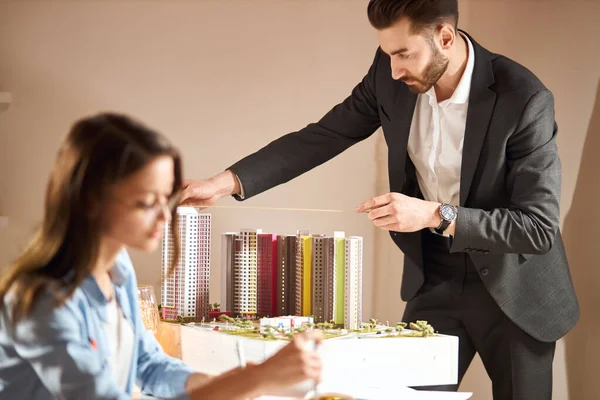 Bearded man in black stylish suit measuring the layout — Stockfoto