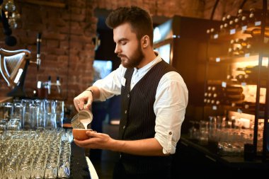 young barmen concentrated on pouring milk to coffee