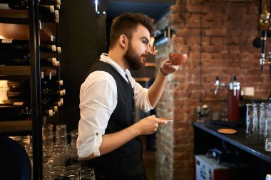 young bearded barista advising customers to buy, drink, taste coffee