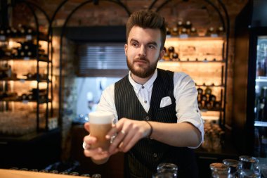 young handsome barmen giving beverage to clients