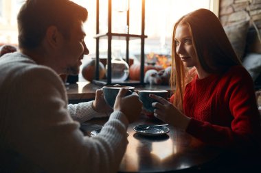 young romantic couple holding cups with yummy flat white, staring at each other