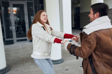 Genç, güzel, gülümseyen kızıl kadın ve sokakta dans eden yakışıklı adam.