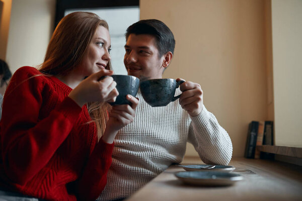 romantic couple sitting at the table enjoying hot tea