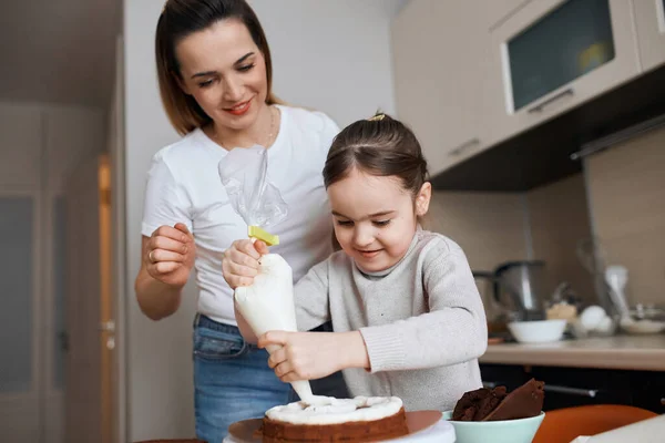 Little girl using pastry bag while cooking cake — Stock Photo, Image