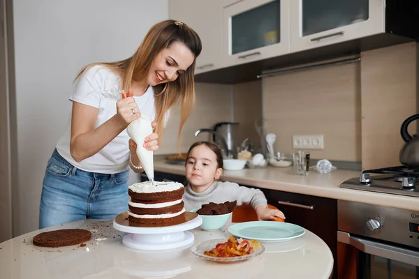 Close shot of a woman and her kid frosting a cake with whipped cream — Stock Photo, Image