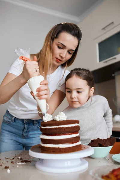 young awesome woman and little girl learning to decorate cake
