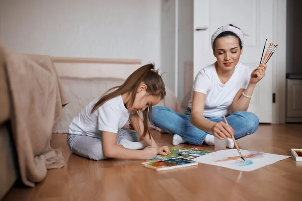 Молодий вчитель допомагає дитині малювати картини — стокове фото