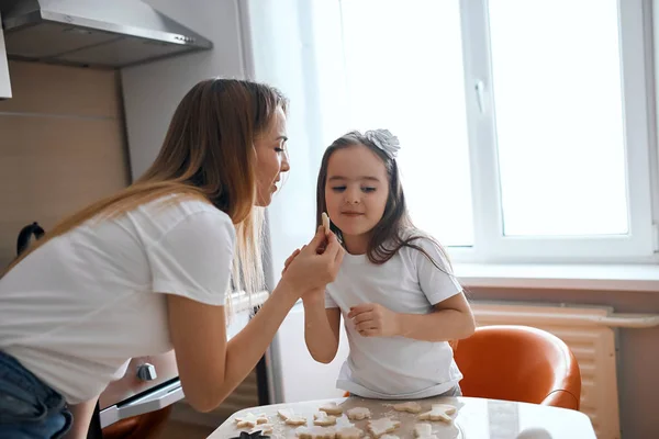 Vonzó nő mutatja, hogyan lehet cookie-kat egy liitle aranyos lány — Stock Fotó