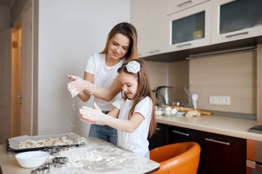 pozitif küçük kız ve kadın mutfakta kurabiye yapıyorlar.