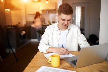 Mutlu adam başarılı anlaşmasıyla seviniyor, kahvaltı ederken notlar alıyor.