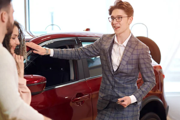 young smart man recommending family to buy red car