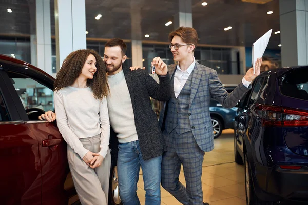 Bärtiger, gutaussehender Mann gibt den Schlüssel für ein neues Luxusauto im Autohaus ab — Stockfoto