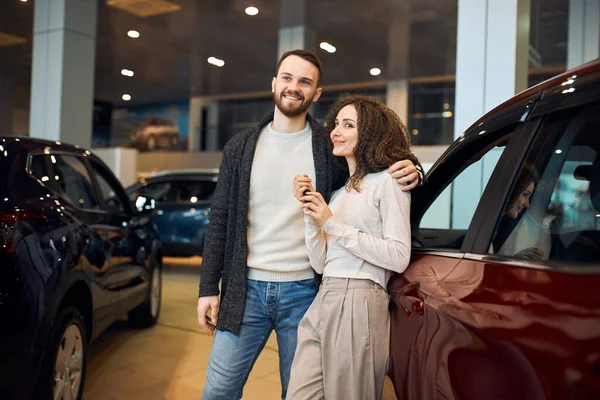 Lächelndes Paar freut sich, dass es Besitzer eines neuen Autos geworden ist — Stockfoto