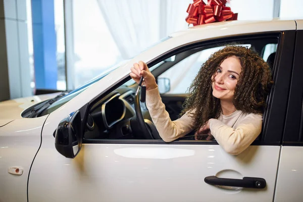 Fröhliches glückliches Mädchen sitzt in ihrem neuen Auto und hält den Schlüssel — Stockfoto