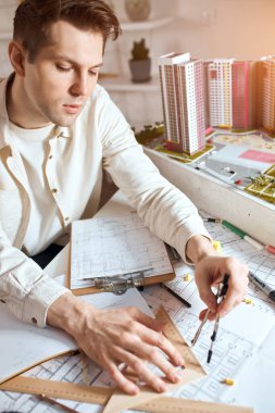 Close-up of young serious man concentrated on using compass for drawing