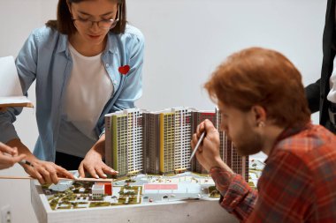 young attractive brunette woman in glasses measuring a model with a ruler