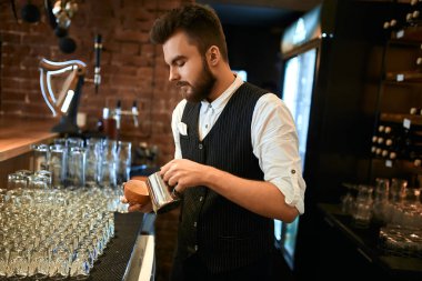 young stylish man in black vest and white shirt selling latte