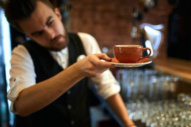 handsome waiter looking at the orange cup and soucer