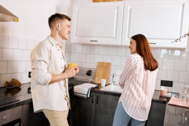 smiling man enjoying watching how his wife doing household chores