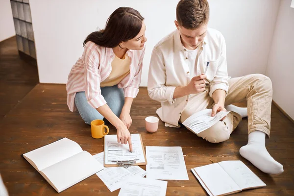 Young family doing paperwork sitting on floor with lot of paper documents — Stock Fotó