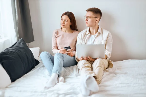 Thoughtful pensive couple sitting on the bed and looking at the window — Stock Photo, Image