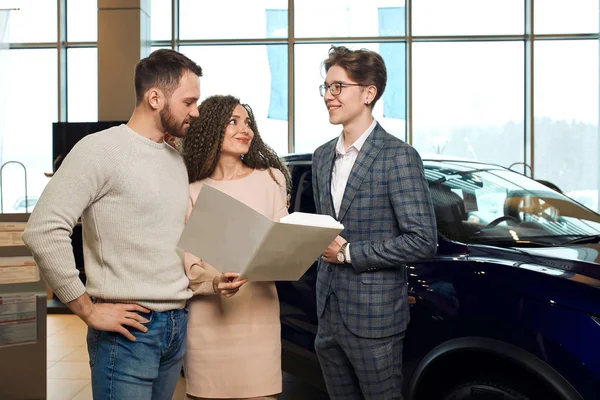 Attractive couple buying a new car from a salesman — Stockfoto