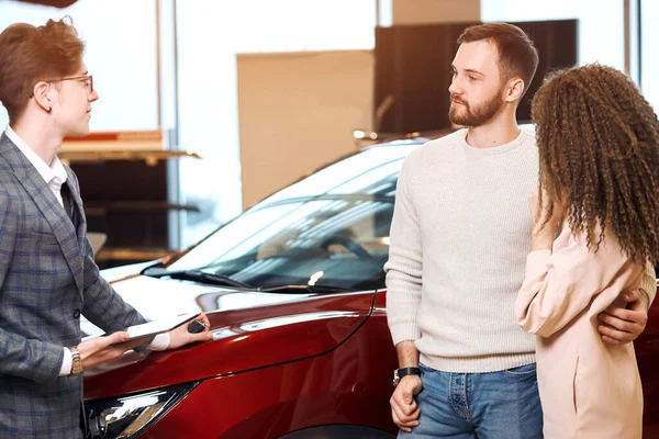 Junge angenehme Manager versuchen, Paar zum Kauf eines Autos zu überreden — Stockfoto