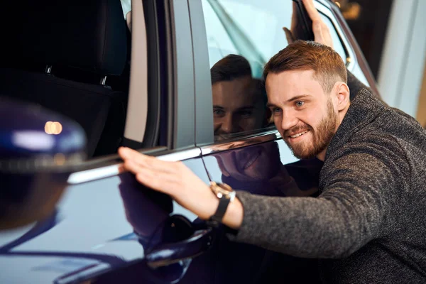 Glücklicher schöner Mann, der sein blaues Auto nach dem Lackieren berührt und repariert — Stockfoto