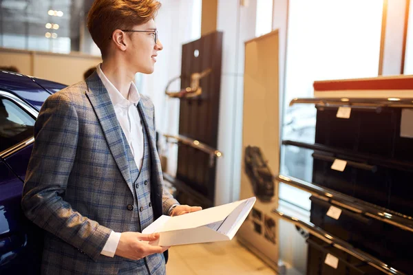 elegant man in glasses and fashion suit holding a contract