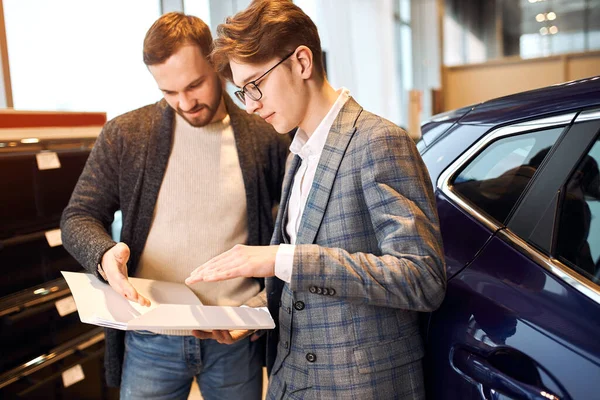 Elegante Verkäuferin und Mann beim Lesen der Merkmale, Vertragsbedingungen — Stockfoto