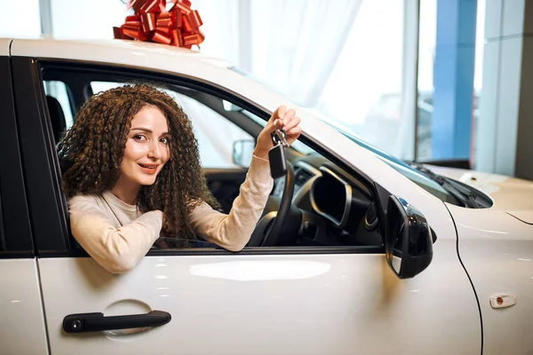 Schöne junge wunderschöne Frau bekommt Schlüssel und lächelt, während sie in einem neuen Auto sitzt — Stockfoto