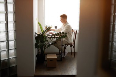 handsome cheerful young man working and typing on laptop at home
